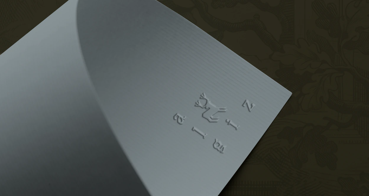 The Algiz wordmark and stag blind embossed into a sheet of grey-blue paper