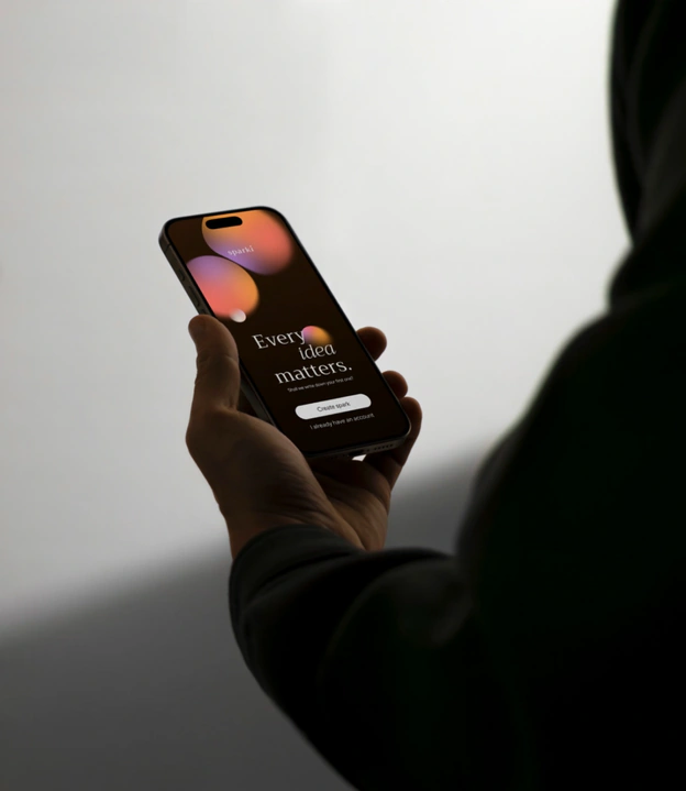 A hand holding a phone showing the Sparki welcome screen