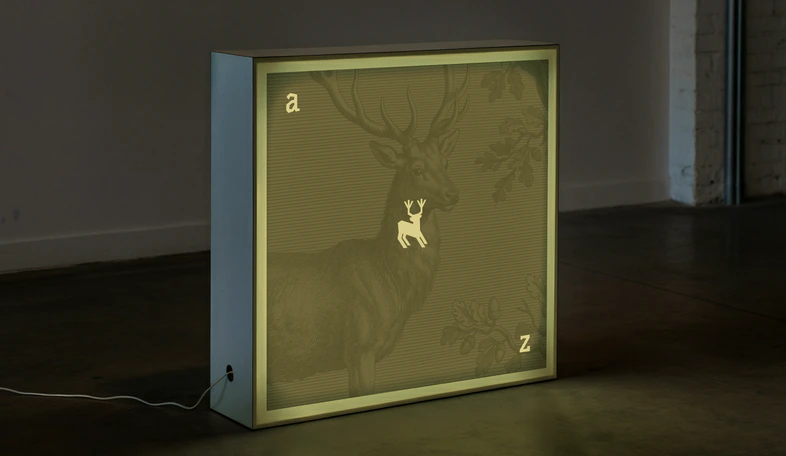 A backlit Algiz display box glowing with an engraved stag in a dim room