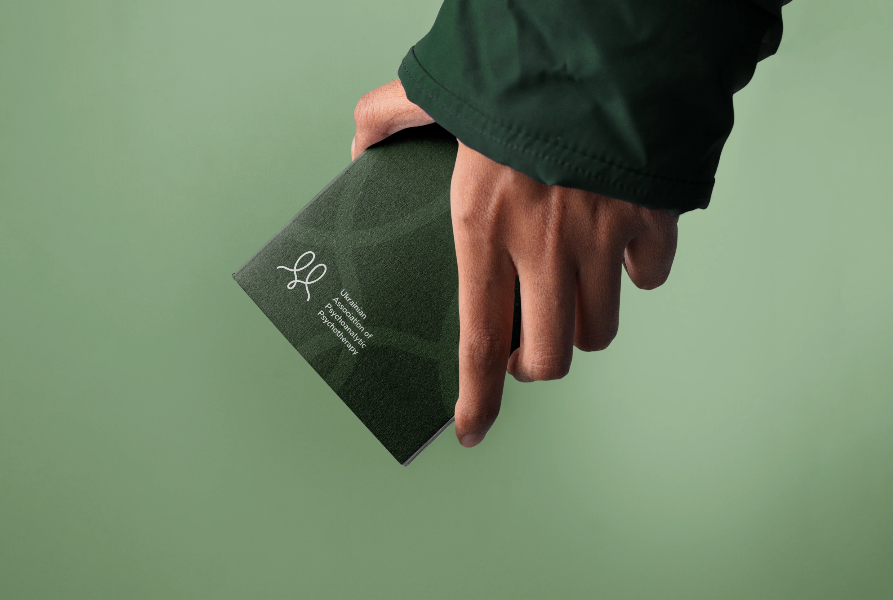 A hand holding a green UAPP booklet
